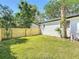 View of the grassy backyard featuring a new wooden fence, lush greenery, and the home's exterior at 5400 Turton Ln, Port Orange, FL 32127