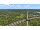 Vast aerial perspective of land with a pond, surrounded by lush green trees and highway at 800 Hidden Oaks Ln, Oak Hill, FL 32759