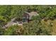 Aerial view of home with a dark roof situated among lush green trees and long driveway at 800 Hidden Oaks Ln, Oak Hill, FL 32759