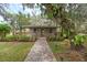 Charming home with a front porch, stone walkway, lush landscaping, and a large tree, offering serene curb appeal at 800 Hidden Oaks Ln, Oak Hill, FL 32759