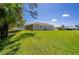 Spacious backyard with lush green grass, views of the house's exterior, and a tranquil pond nearby at 823 Wooddusk Dr, Port Orange, FL 32127