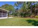Expansive backyard featuring a well-maintained lawn, mature landscaping, and a view of the tranquil pond at 823 Wooddusk Dr, Port Orange, FL 32127