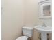 Cozy bathroom featuring a toilet, pedestal sink, and a decorative mirror at 825 Baltimore Dr, Orlando, FL 32810