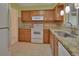 Traditional kitchen with wood cabinetry, tile floor, and stainless steel sink at 101 Grand Plaza Dr # A30, Orange City, FL 32763