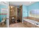 Bright bathroom featuring walk-in shower with glass door, tiled surround tub, and a toilet at 105 Riviera Estates Blvd, Ormond Beach, FL 32174