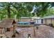 Backyard featuring a pool, a play structure, and surrounded by lush trees, creating a serene environment at 1135 5Th St, Orange City, FL 32763