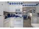 Bright kitchen featuring white appliances, cabinets, blue decorations, and dining nook with blue and white checkered pattern at 1148 Briarwood Ave, Deltona, FL 32725