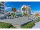 Large deck area with tables and chairs, umbrellas, and tropical landscaping near beach and condominium at 1167 Ocean Shore Blvd # 110, Ormond Beach, FL 32176