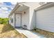 Close up on home's front door with white siding, a small garden, and a well-lit entryway at 1229 Saddleback Ridge Rd, Apopka, FL 32703