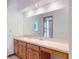 Bathroom vanity with double sinks and a large mirror reflecting the shower at 1371 Merrifield Ct, Deltona, FL 32725