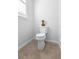 Modern bathroom showcases a toilet with a decorative vase, window with blind, and neutral tile flooring at 1374 Red Clover Ln, Deland, FL 32724