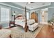 Bright and airy primary bedroom featuring a four-poster bed, hardwood floors, and comfortable decor at 1420 Shady Meadow Ln, Deland, FL 32724