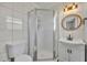 Well-lit bathroom featuring a glass-enclosed shower, toilet, vanity, and round wooden mirror at 150 Reef Rd, South Daytona, FL 32119
