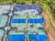 Overhead view of multi-colored tennis courts with some visible wear, set among lush greenery at 161 Blue Heron Dr # C, Daytona Beach, FL 32119