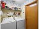 Laundry room with white washer and dryer, shelving, and a wood-paneled door at 1731 Urbana Ave, Deltona, FL 32725