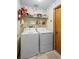 Laundry room with white washer and dryer, shelving, and a wood-paneled door at 1731 Urbana Ave, Deltona, FL 32725
