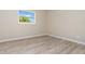 Bright bedroom with wood-look flooring, neutral walls, and natural light from the window at 1808 Green Pl, Ormond Beach, FL 32174