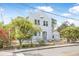 Front exterior shows a quaint white home, lush trees and a chain-link fence at 216 Earl St, Daytona Beach, FL 32118