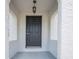 Close-up view of a classic black front door with textured white pillars and a vintage pendant light above at 216 Earl St, Daytona Beach, FL 32118