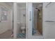 Compact bathroom featuring toilet, shower with blue curtain, neutral tile, and convenient grab bar for accessibility at 220 Buena Vista St, Debary, FL 32713