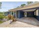 Carport of a blue home, with a concrete floor, white lattices, and a white door on the side at 220 Buena Vista St, Debary, FL 32713