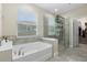 Bathroom with a luxurious soaking tub, a glass-enclosed shower, and a glimpse of a walk-in closet through an open door at 2337 Oxmoor Dr, Deland, FL 32724