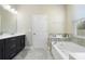 Well-lit bathroom featuring a double vanity, a bathtub, and an alcove for bath products with a large framed mirror at 2337 Oxmoor Dr, Deland, FL 32724