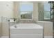 Relaxing bathtub with tile surround, built-in shelves, and a clear window for natural light, and sleek silver fixtures at 2337 Oxmoor Dr, Deland, FL 32724