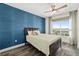 Well-lit bedroom with a textured blue accent wall, a ceiling fan, and a view of the city at 241 Riverside Dr # 902, Holly Hill, FL 32117
