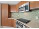 Close up of kitchen featuring stainless steel appliances, wood cabinets and an attractive backsplash at 241 Riverside Dr # 902, Holly Hill, FL 32117