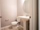 Bathroom featuring a pedestal sink, toilet, and a round mirror in a room with neutral-colored walls at 258 Rustic Loop, Sanford, FL 32771