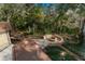 Aerial view of a backyard with a wooden deck, fire pit, and seating area amidst lush greenery at 2628 Spruce Creek Blvd, Port Orange, FL 32128