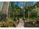 Landscaped backyard pathway leading to wooded area with decorative lighting and comfortable seating at 2628 Spruce Creek Blvd, Port Orange, FL 32128