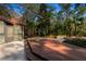 Exterior view of a backyard with a wooden deck, stairs, and view of landscaping with mature trees at 2628 Spruce Creek Blvd, Port Orange, FL 32128