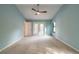 Pastel bedroom with ceiling fan, large window, and door to outdoor balcony at 2628 Spruce Creek Blvd, Port Orange, FL 32128