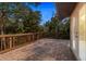 Spacious deck featuring a brick floor, wood railings, and views of the surrounding trees at 2628 Spruce Creek Blvd, Port Orange, FL 32128