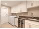 Well-appointed laundry room featuring ample storage, stainless steel appliances, and a convenient wine fridge at 2628 Spruce Creek Blvd, Port Orange, FL 32128