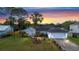 Beautiful single-story home with a manicured lawn, swaying palm tree, and vibrant sunset backdrop at 3214 Juniper Dr, Edgewater, FL 32141