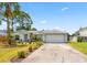 Well-maintained single-story home with a long driveway, lush landscaping, and a two-car garage at 3214 Juniper Dr, Edgewater, FL 32141