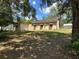 View of the home from the expansive backyard, surrounded by trees at 326 South St, De Leon Springs, FL 32130