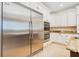 Kitchen showing a stainless steel refrigerator, custom white cabinetry, granite counters, and built-in ovens at 33 Ocean Shore Blvd, Ormond Beach, FL 32176