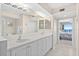 Bright bathroom featuring a double vanity, neutral tile floor, and an open doorway to the bedroom at 3311 S Atlantic Ave # 1704, Daytona Beach Shores, FL 32118