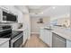 Bright kitchen features stainless steel appliances, mosaic tile backsplash, and white cabinetry with light wood flooring at 3311 S Atlantic Ave # 1704, Daytona Beach Shores, FL 32118