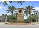 A beige colored clock tower stands tall behind lovely palm trees and manicured bushes at 3451 Luna Bella Ln, New Smyrna Beach, FL 32168