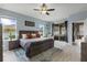Bright main bedroom featuring wood-look floors, large windows, ceiling fan, and sliding door access to the lanai at 3451 Luna Bella Ln, New Smyrna Beach, FL 32168