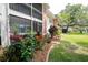 Serene backyard with lush lawn, shade tree, colorful flowerbeds, and partial patio views at 3800 Saxon Dr # 150, New Smyrna Beach, FL 32169