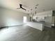 Open-concept living room with gray floors, modern lighting, and a kitchen island with granite countertops at 516 Model St, Daytona Beach, FL 32114