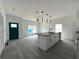 Spacious living room featuring gray floors, a kitchen island with seating, and modern lighting fixtures at 516 Model St, Daytona Beach, FL 32114