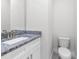 Elegant half-bathroom with a granite countertop sink and a toilet with a tiled floor at 561 Coronado Cove Road, New Smyrna Beach, FL 32168