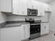 Modern kitchen with white cabinets, granite countertops, and stainless steel appliances at 561 Coronado Cove Road, New Smyrna Beach, FL 32168